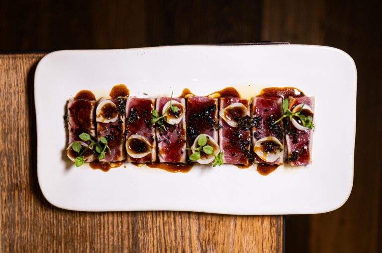 Tataki de atún rojo con cebollita asada, algas y sésamo negro, plato de Bar Cañete